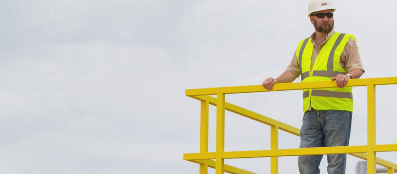 Worker standing on platform with a custom, yellow Fiberglass Reinforced Plastic handrail.