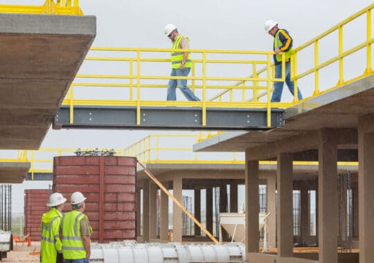 Workers in outside electrical substation using walkways made from yellow ReadyPlatform and ReadyRail products.