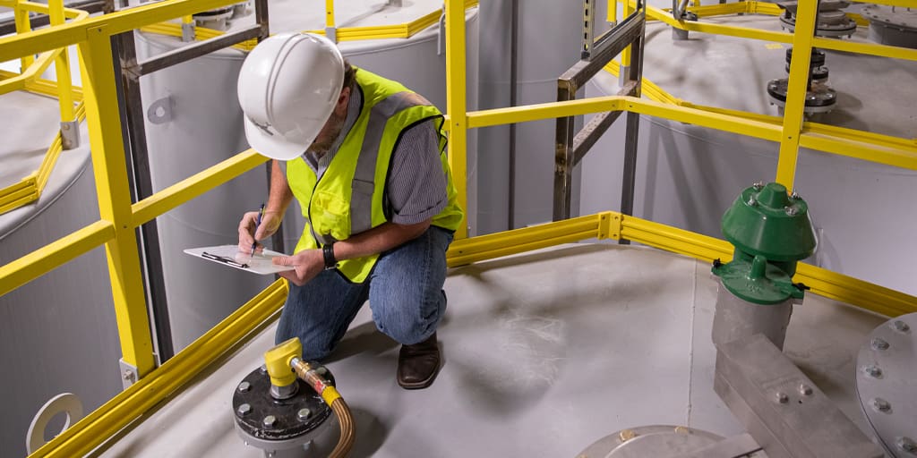 Engineer inspecting jobsite with yellow FRP railings inside a well lit building