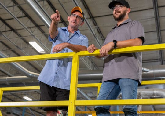 image of two men leaning on yellow FRP railing in an industrial setting