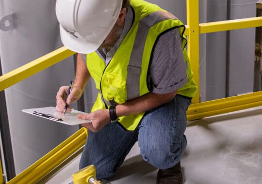 Engineer inspecting jobsite with fiberglass reinforced plastic products inside a well lit building