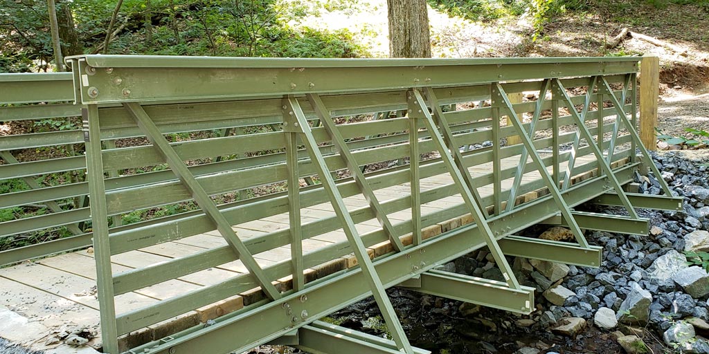 iberglass-reinforced polymer pedestrian bridge on gravel trail.